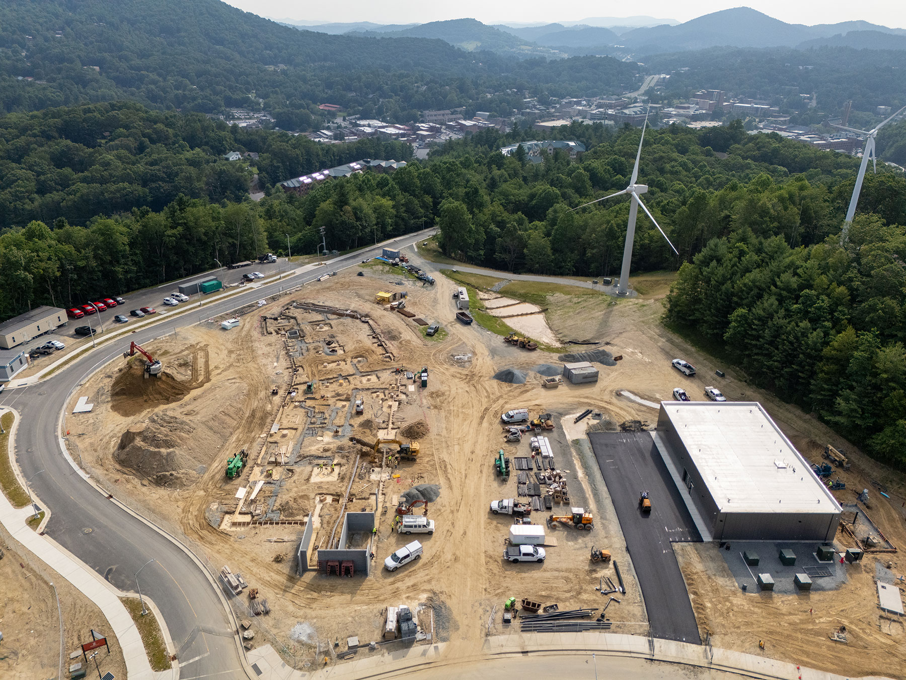 Aerial view of energy control building, STEM building site, and wind turbines at App State.